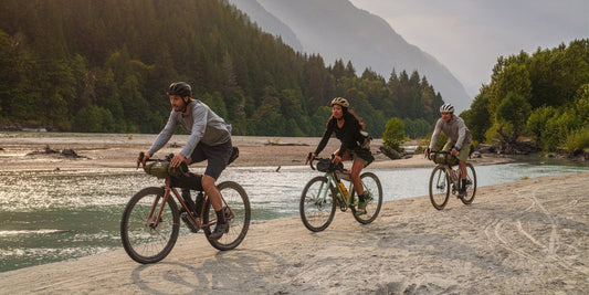 Three people bikepacking along a river.