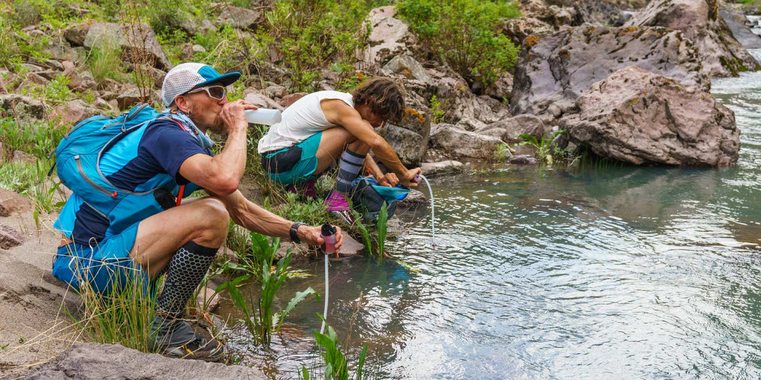 Hikers refilling water bottles at stream with TrailShot Microfilters