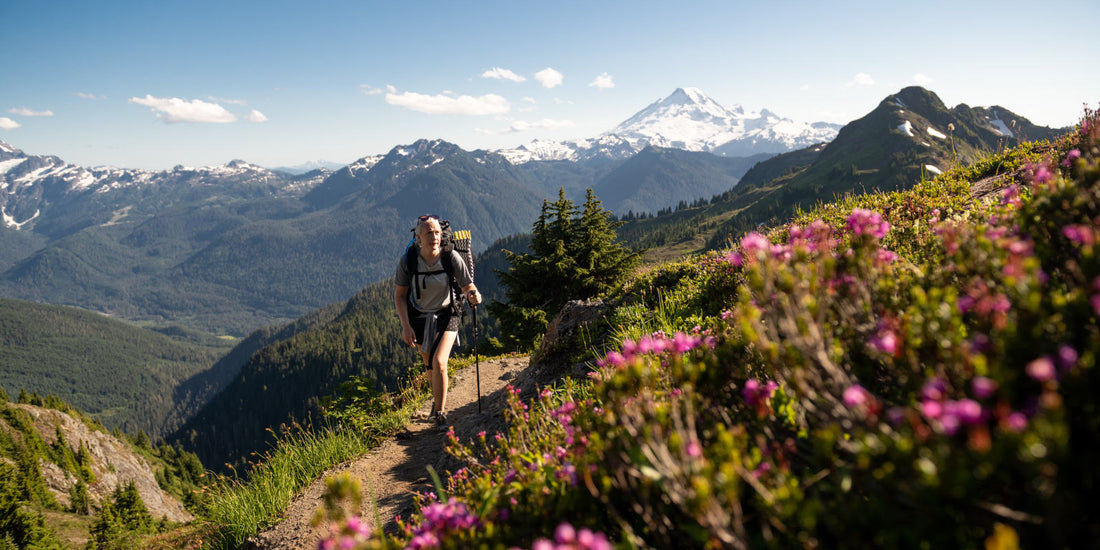 Thru-hiker on trail with mountains behind