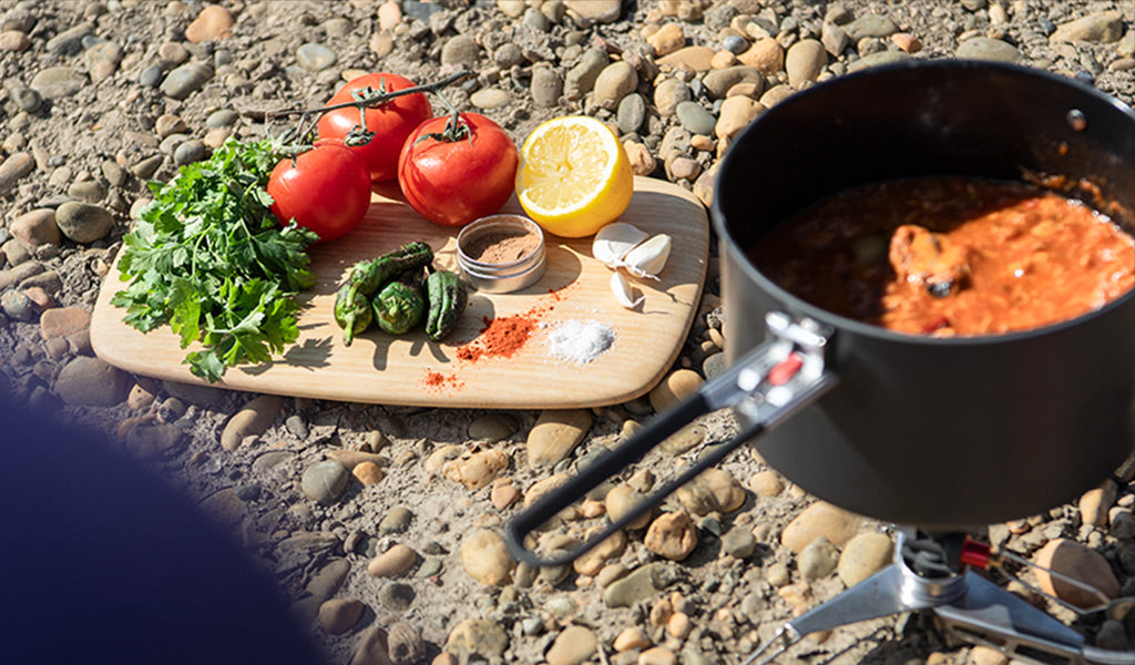 Pot filled with Chili and cutting board with vegetables