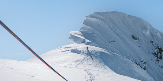 Mountaineer attached to rope ascending snowy mountain