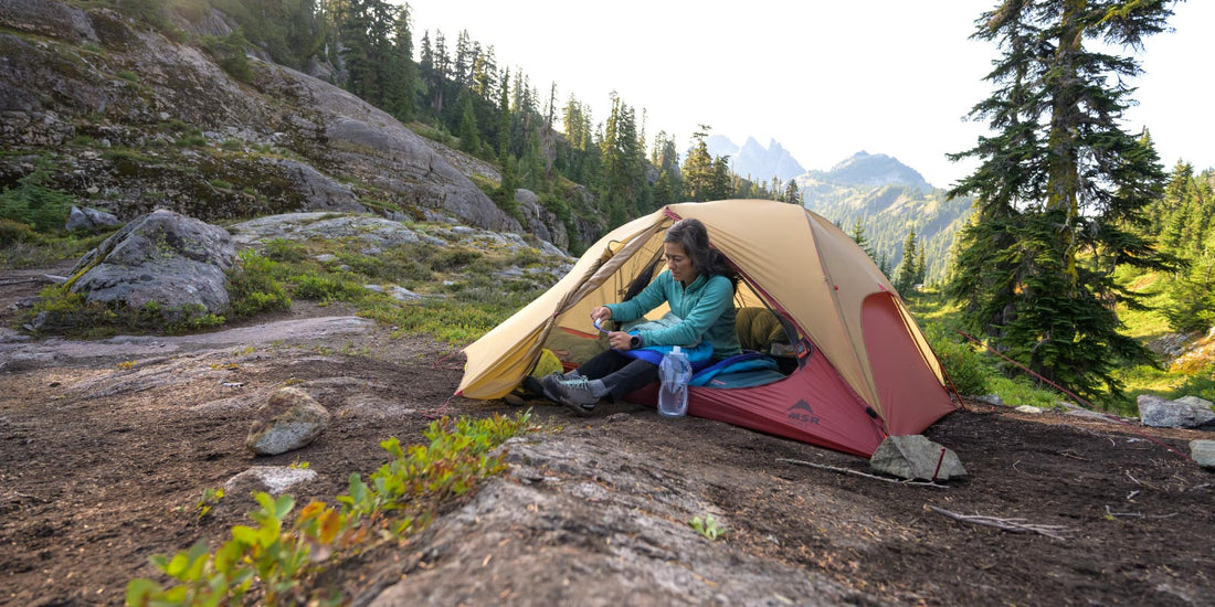 Woman preparing to brush her teeth while sitting in MSR tent