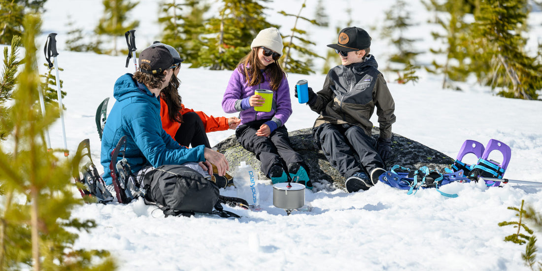 Family breaks for snacks and warm beverages on snowshoe adventure