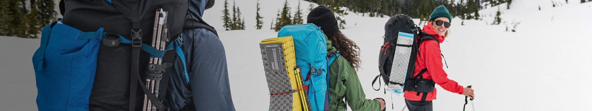 A couple hiking on a forest trail wearing large outdoor backpacks