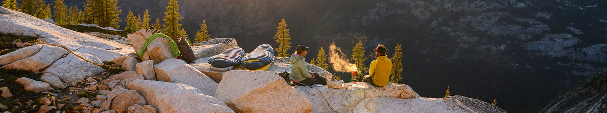 Backpackers resting at an alpine overlook with lightweight Therm-a-Rest sleeping pads and fast and light backpacking gear in a mountain wilderness setting.